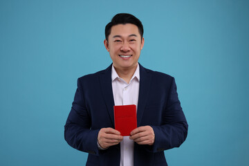 Immigration. Happy man with passport on light blue background