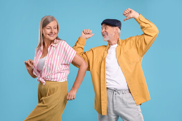Senior couple dancing together on light blue background