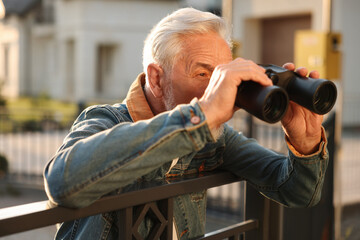 Concept of private life. Curious senior man with binoculars spying on neighbours over fence outdoors - obrazy, fototapety, plakaty