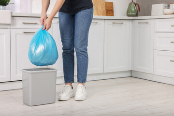 Woman taking garbage bag out of trash bin in kitchen, closeup - obrazy, fototapety, plakaty