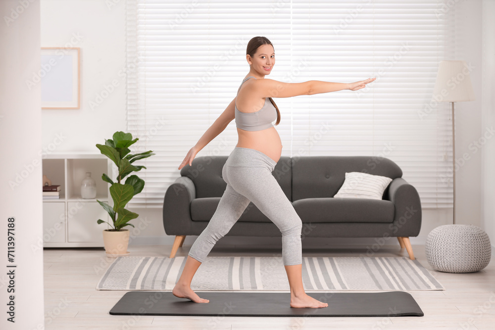 Poster Pregnant woman doing exercises on yoga mat at home