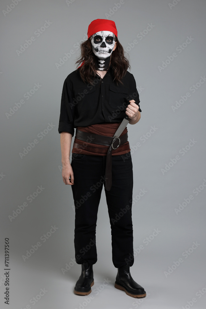 Sticker Man in scary pirate costume with skull makeup and knife on light grey background. Halloween celebration