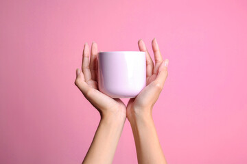Woman's hand holding beige cup mockup isolated over pink background