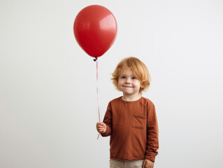 Fototapeta na wymiar Caucasian boy holding red balloon on white background