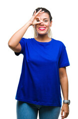 Fototapeta premium Young beautiful woman wearing casual blue t-shirt over isolated background doing ok gesture with hand smiling, eye looking through fingers with happy face.