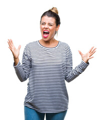 Young beautiful woman casual stripes sweater over isolated background crazy and mad shouting and yelling with aggressive expression and arms raised. Frustration concept.