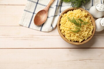 Tasty millet porridge and dill in bowl on light wooden table, flat lay. Space for text