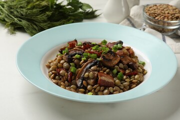 Delicious lentils with mushrooms, bacon and green onion on white table, closeup