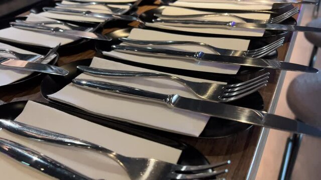 Knife and fork prepared on an empty table in a restaurant. serving knives and forks on white napkins on a large long table preparation for a corporate event of a large company cutlery