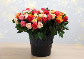 Bouquet of beautiful roses on wooden table against light background