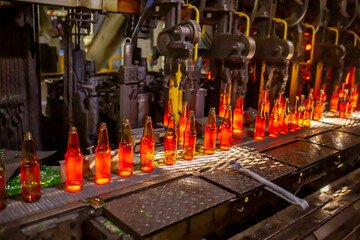 Glass factory, production of glass containers. Molten glass is blown into molds. Robotics in industry. Modern technologies, robotic machines produce products. Technological work at the plant.