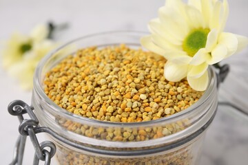 Fresh bee pollen granules in jar and flower, closeup