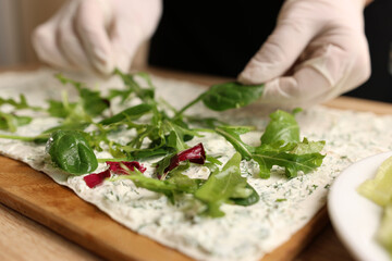 Greens are added to pita bread with cheese. Preparation of a roll with cheese, fish and vegetables