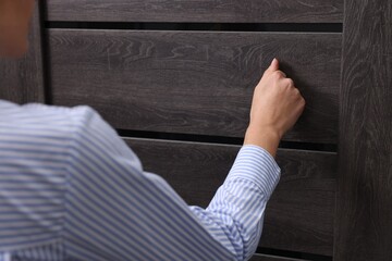 Woman knocking on door indoors, closeup view