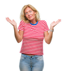 Middle age blonde woman over isolated background clueless and confused expression with arms and hands raised. Doubt concept.