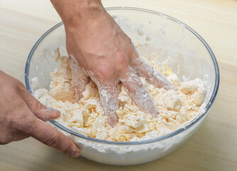 Wyrabiać ciasto w misce, zbliżenie ma dłoń i składniki 