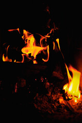 Fire in the fireplace black background. Red and yellow flame blaze, thermal energy during the night