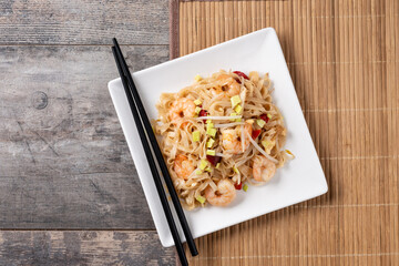 Pad Thai with shrimp and vegetables on wooden table. Top view. Copy space