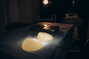 Surgical scissors, tweezers, scalpel and silicone breast implant on operating table. Clinic of...