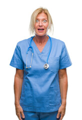 Middle age blonde nurse surgeon doctor woman over isolated background afraid and shocked with surprise expression, fear and excited face.