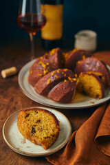 Delicious homemade pumpkin bundt cake with prunes and sherry, decorated with frosting and zest on a wooden background.