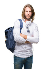 Young handsome tourist man with long hair wearing backpack over isolated background skeptic and nervous, disapproving expression on face with crossed arms. Negative person.