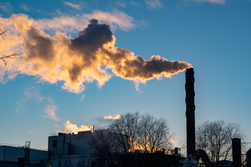 Big chimney with lots of smoke and clear blue sky