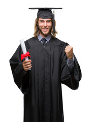 Young handsome graduate man with long hair holding degree over isolated background screaming proud...