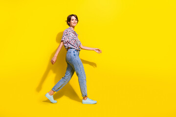 Full length profile photo of cute positive person walking empty space isolated on bright yellow...