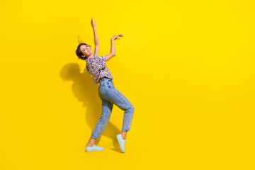 Full length profile portrait of cheerful lovely person raise arms dance rejoice empty space isolated on yellow color background