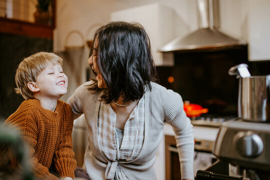 Mother and young son laughing together in home kitchen