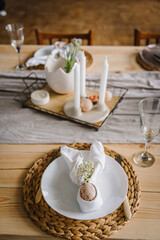 Setting table for Easter dinner with ceramic plates with bunny made of linen napkin and easter egg. Holidays celebration concept. Set up on festive table. Top view. Easter decor with candles at home.