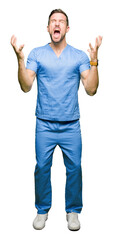 Handsome doctor man wearing medical uniform over isolated background celebrating mad and crazy for...