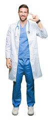 Handsome doctor man wearing medical uniform over isolated background smiling and confident gesturing with hand doing size sign with fingers while looking and the camera. Measure concept.