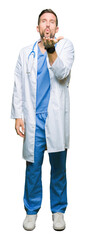 Handsome doctor man wearing medical uniform over isolated background looking at the camera blowing a kiss with hand on air being lovely and sexy. Love expression.