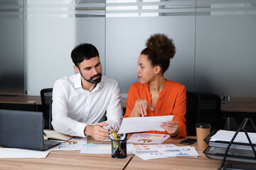 Fototapeta premium Happy young entrepreneurs having a discussion while sitting together at a table.