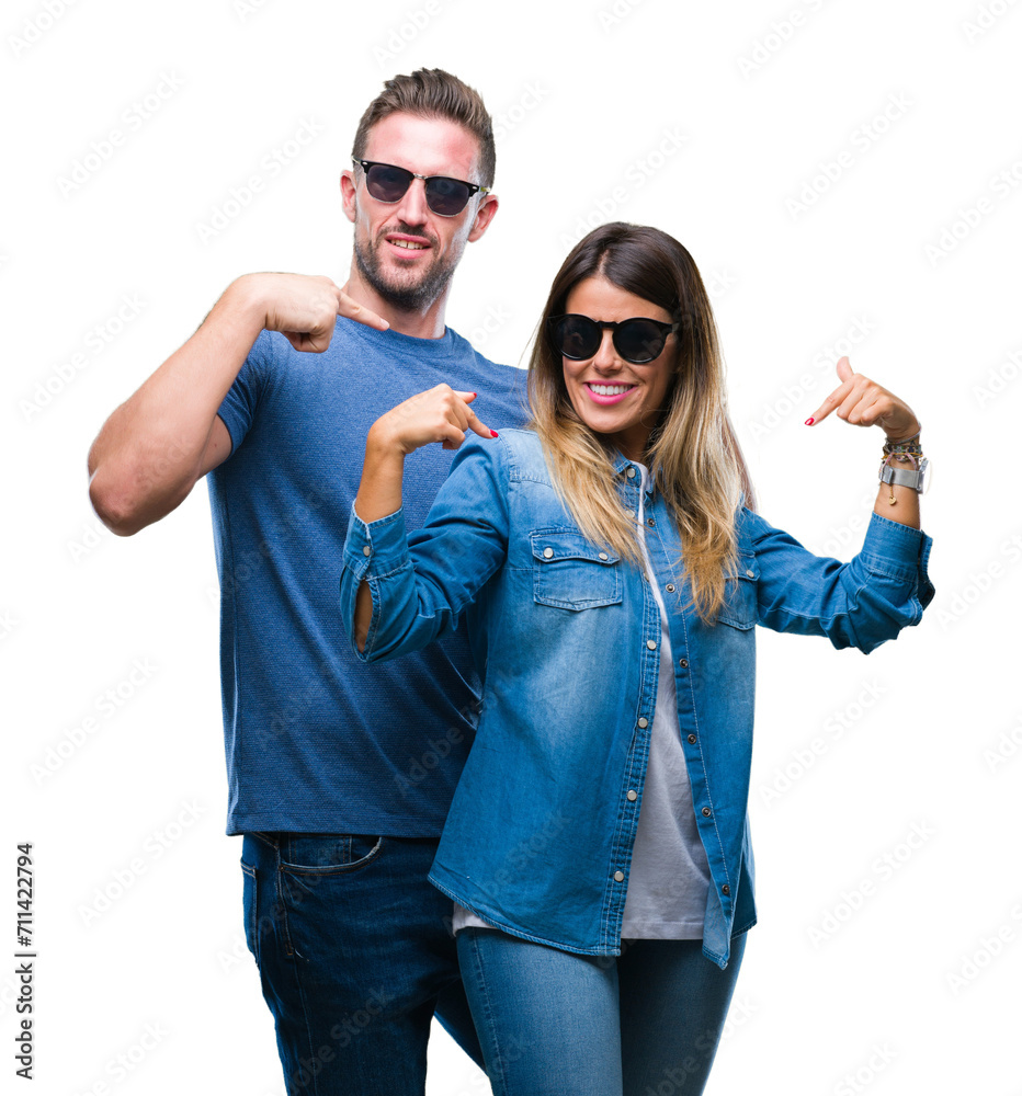 Poster Young couple in love wearing sunglasses over isolated background looking confident with smile on face, pointing oneself with fingers proud and happy.