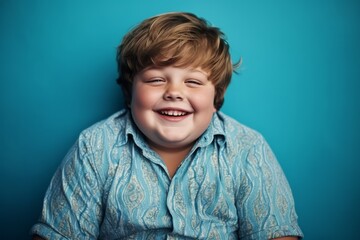 Joyful Young Boy Laughing Against a Teal Background
