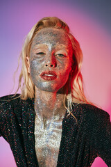 portrait of shiny woman with glitter makeup and sparkling dress posing on pink purple gradient