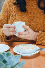 vertical image of pudding on plate with unrecognizable woman in background holding cup of coffee, coffee shop concept