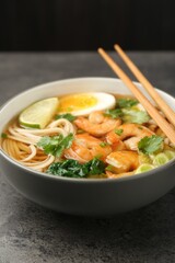 Delicious ramen with shrimps and chopsticks on grey table, closeup. Noodle soup
