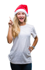 Young beautiful blonde woman wearing christmas hat over isolated background pointing finger up with successful idea. Exited and happy. Number one.