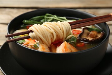 Bowl of delicious ramen with chopsticks on table, closeup. Noodle soup - obrazy, fototapety, plakaty