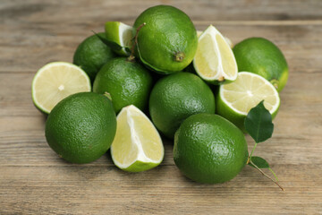 Pile of fresh limes and leaves on wooden table, closeup