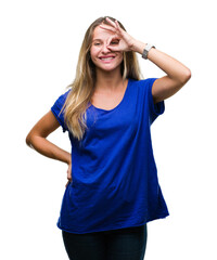 Fototapeta premium Young beautiful blonde woman over isolated background doing ok gesture with hand smiling, eye looking through fingers with happy face.