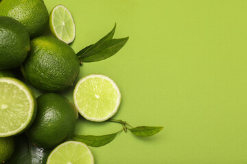 Pile of fresh limes and leaves on green background, flat lay. Space for text