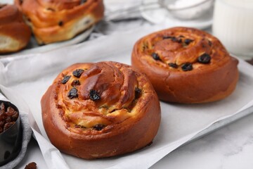 Delicious rolls with raisins on white table, closeup. Sweet buns