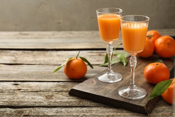 Delicious tangerine liqueur and fresh fruits on wooden table, space for text