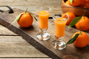 Delicious tangerine liqueur and fresh fruits on wooden table, space for text