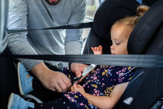 Dad buckling toddler into extended rear facing car seat
